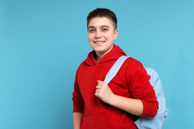 Photo of Teenage boy with backpack on light blue background, space for text