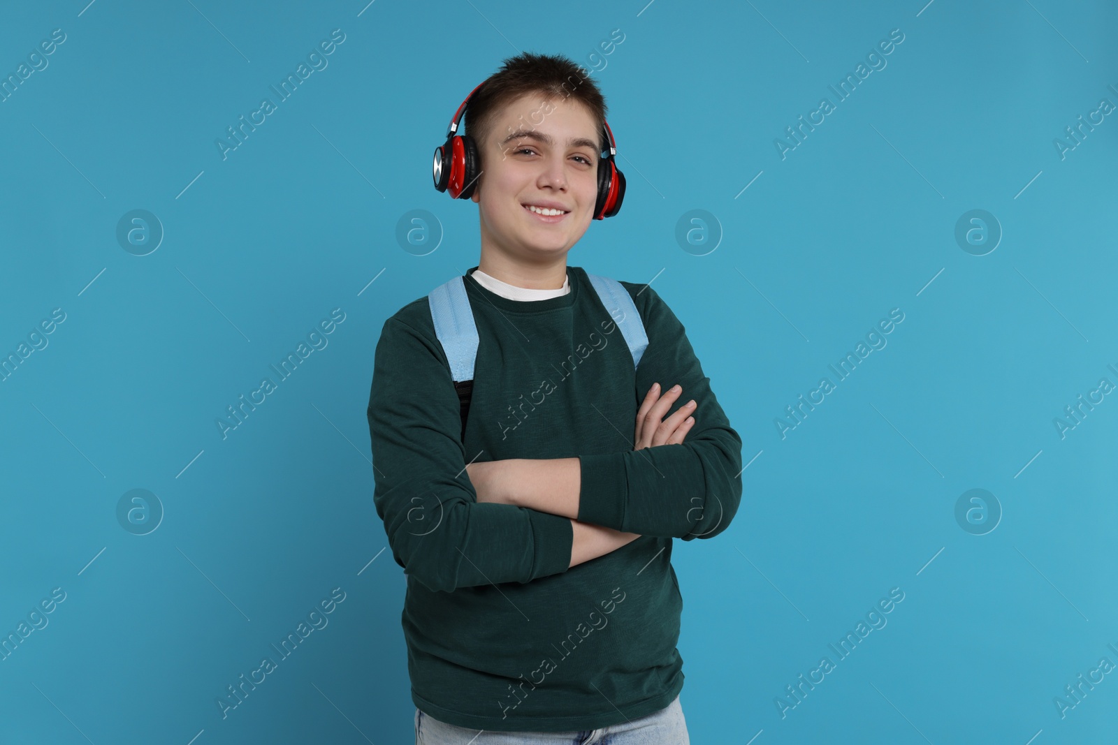 Photo of Teenage boy with backpack and headphones on light blue background