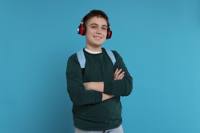 Photo of Teenage boy with backpack and headphones on light blue background