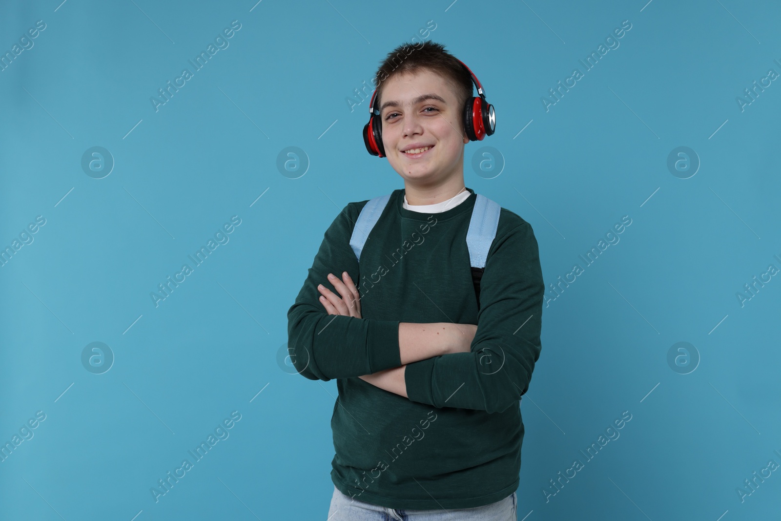 Photo of Teenage boy with backpack and headphones on light blue background