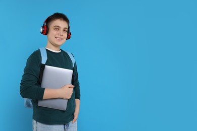 Photo of Teenage boy with backpack, headphones and laptop on light blue background, space for text