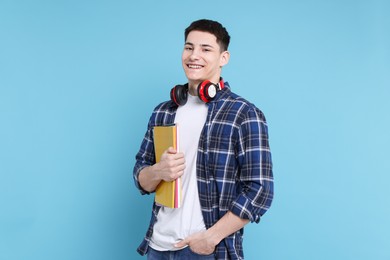 Photo of Student with notebooks and headphones on light blue background