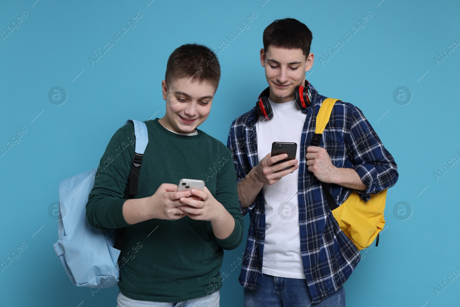 Photo of Students with smartphones and backpacks on light blue background