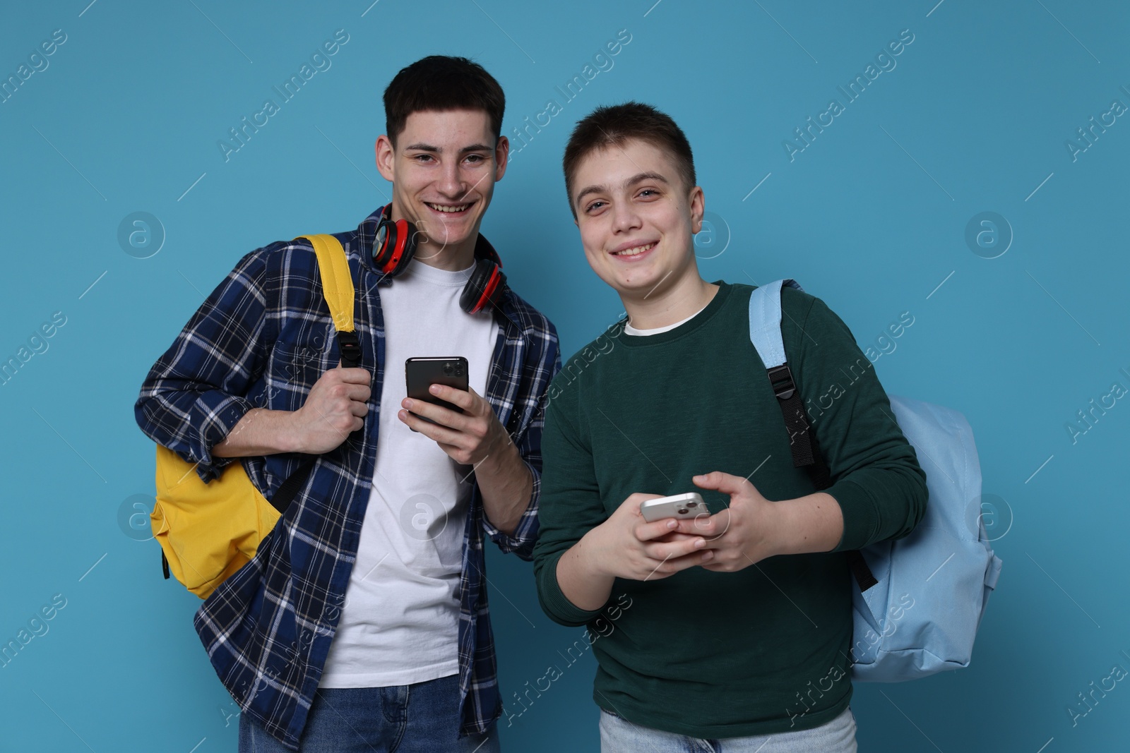 Photo of Students with smartphones and backpacks on light blue background