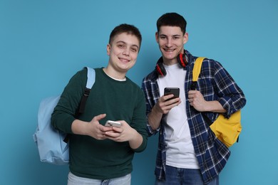 Photo of Students with smartphones and backpacks on light blue background