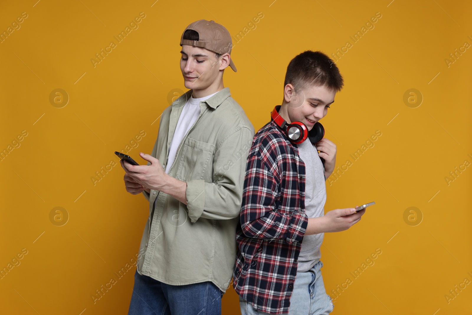 Photo of Portrait of students with smartphones on orange background