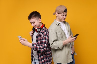 Photo of Portrait of students with smartphones on orange background