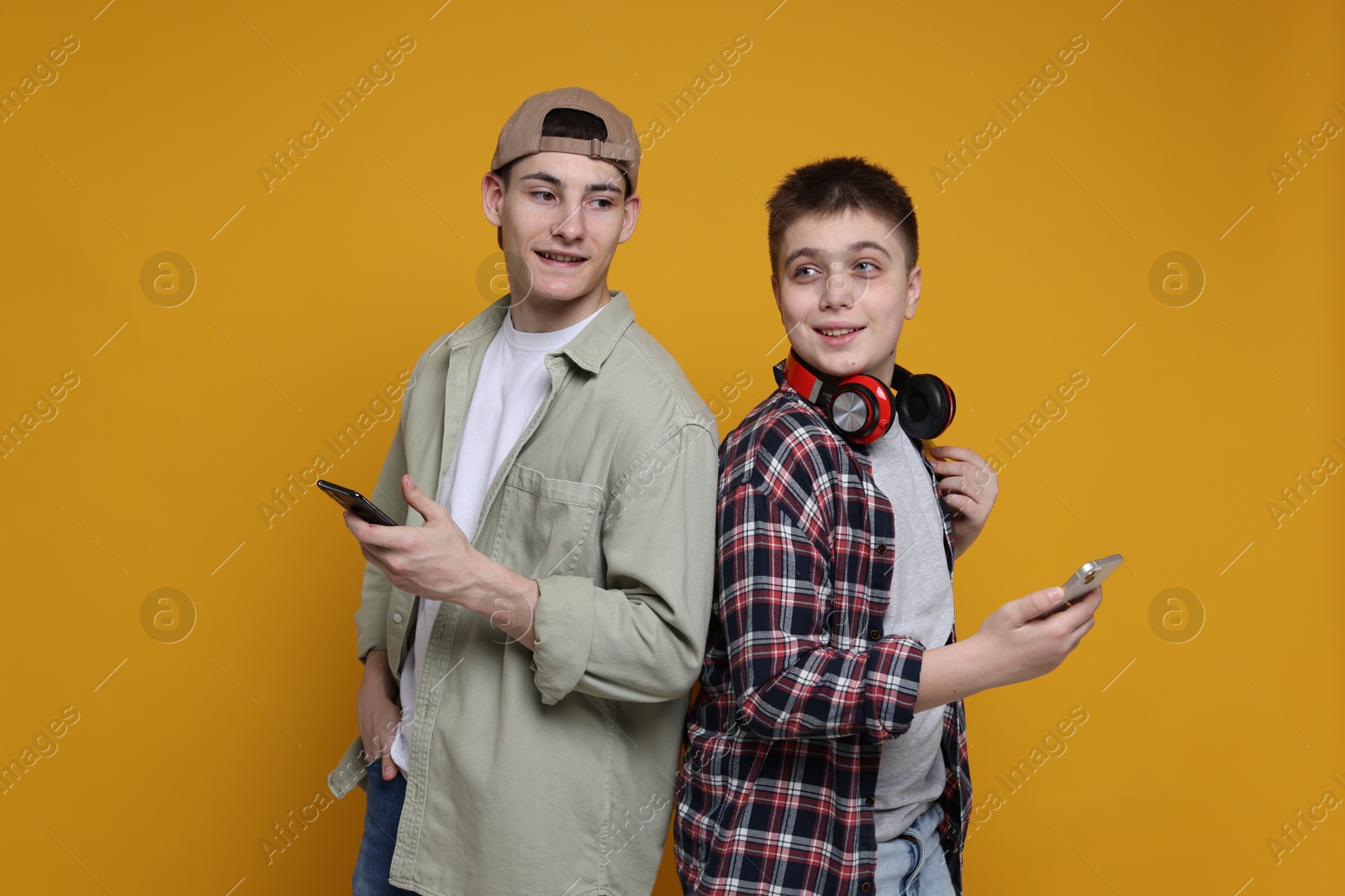 Photo of Portrait of students with smartphones on orange background