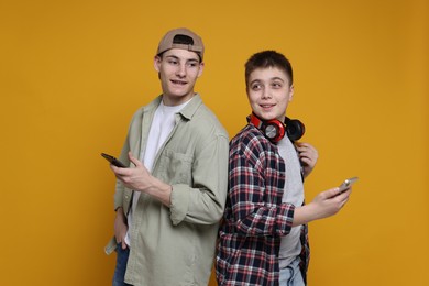 Portrait of students with smartphones on orange background