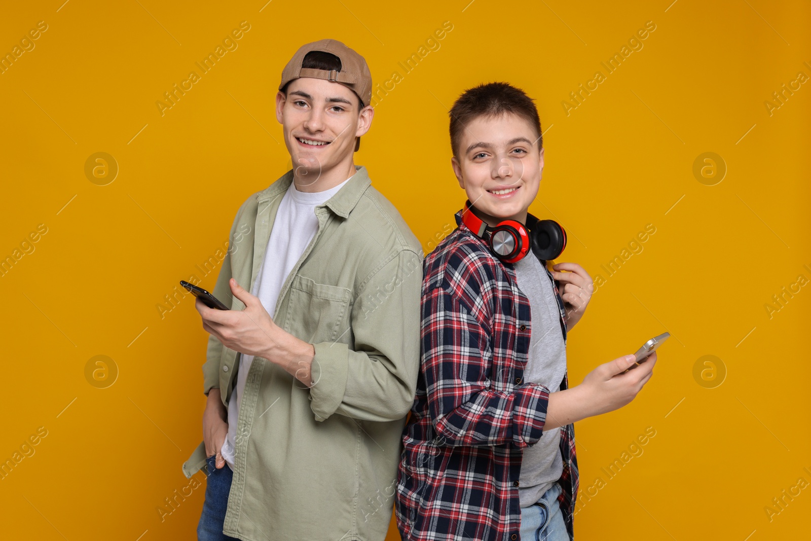 Photo of Portrait of students with smartphones on orange background