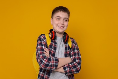 Teenage boy with headphones and backpack on orange background