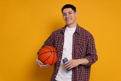 Photo of Student with basketball ball and can of drink on orange background