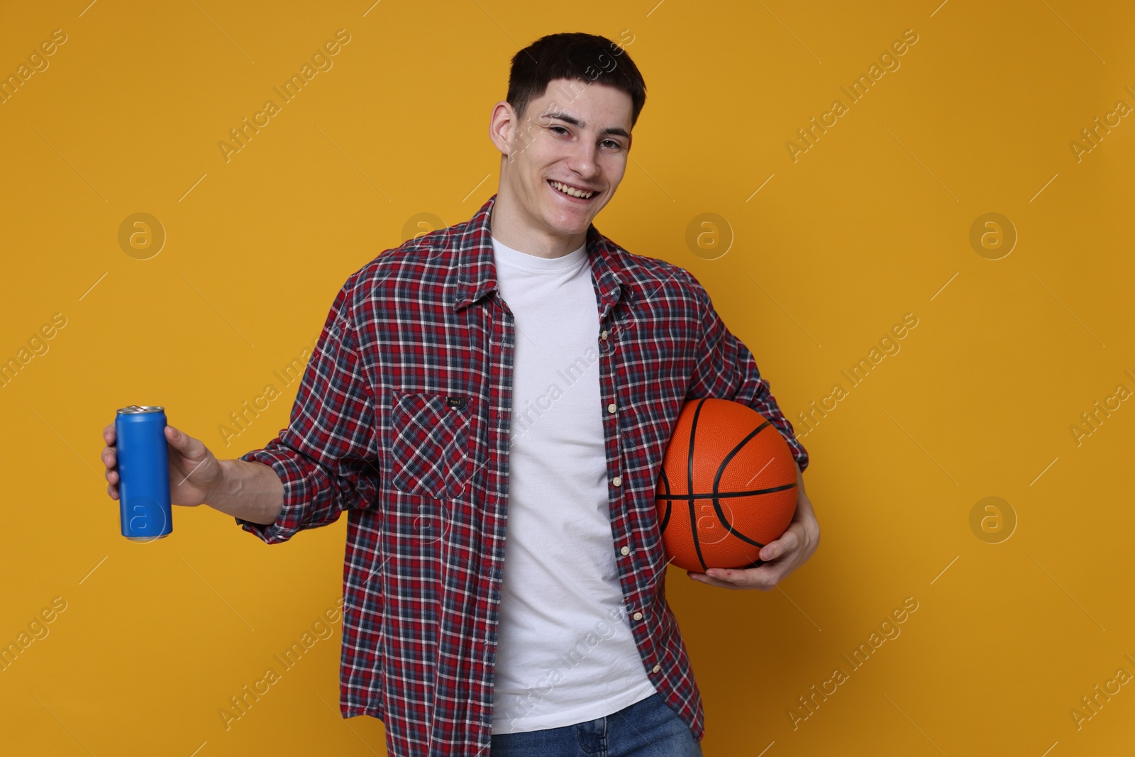 Photo of Student with basketball ball and can of drink on orange background