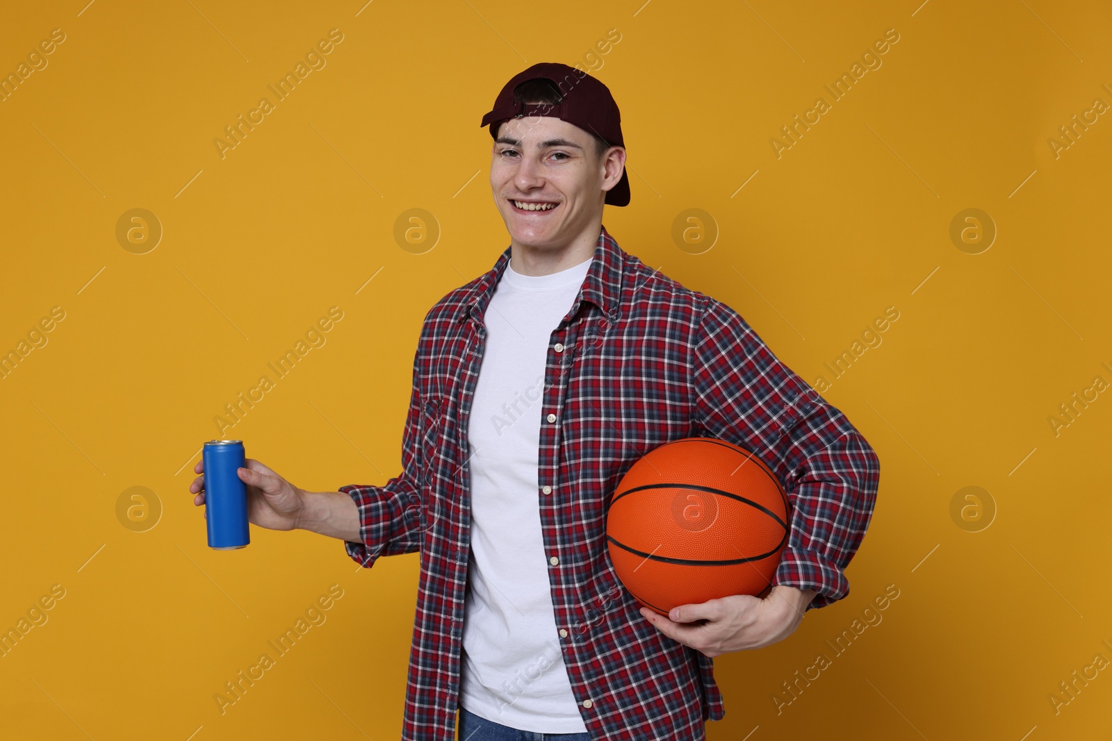 Photo of Student with basketball ball and can of drink on orange background