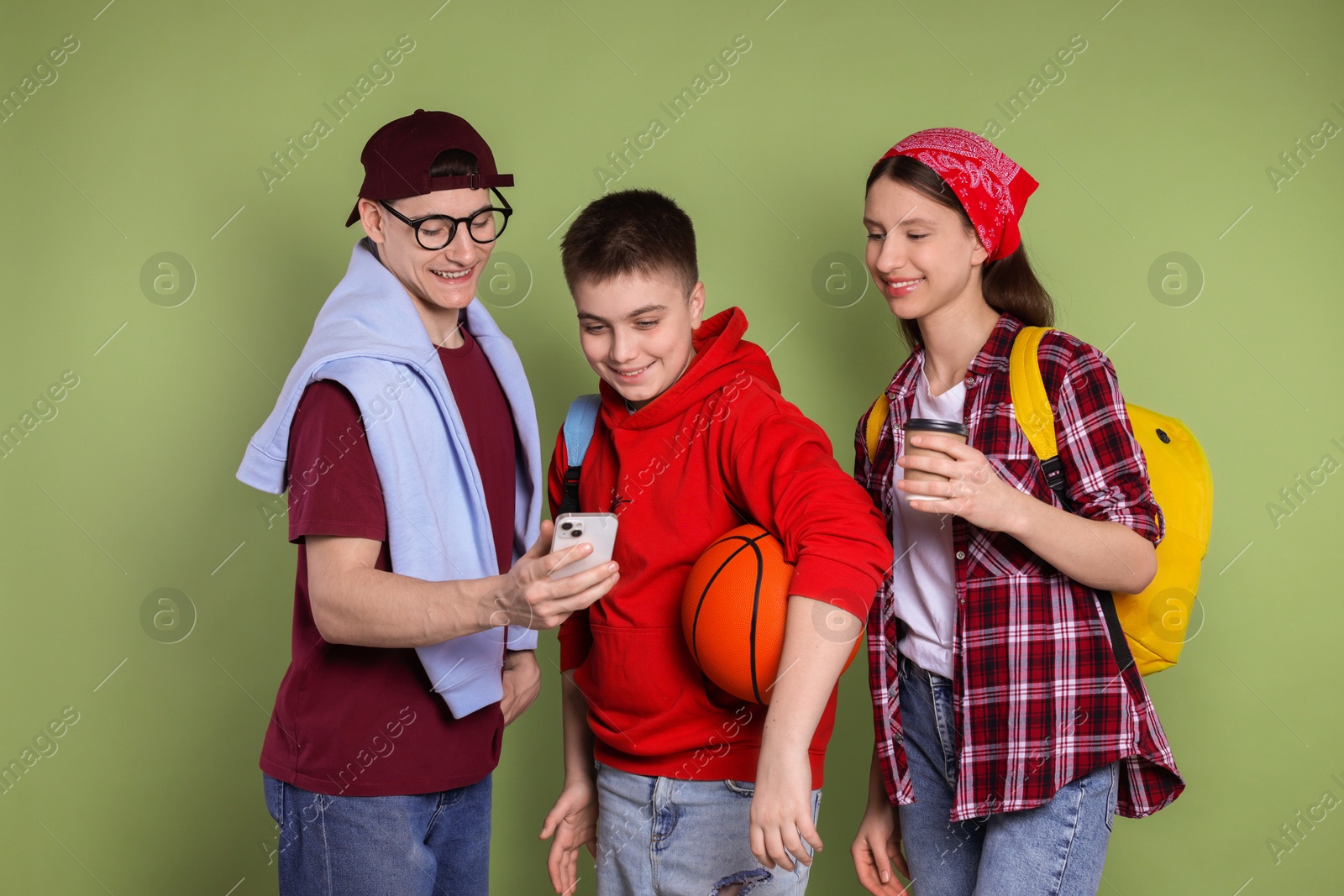 Photo of Student showing something on smartphone to his friends against olive background