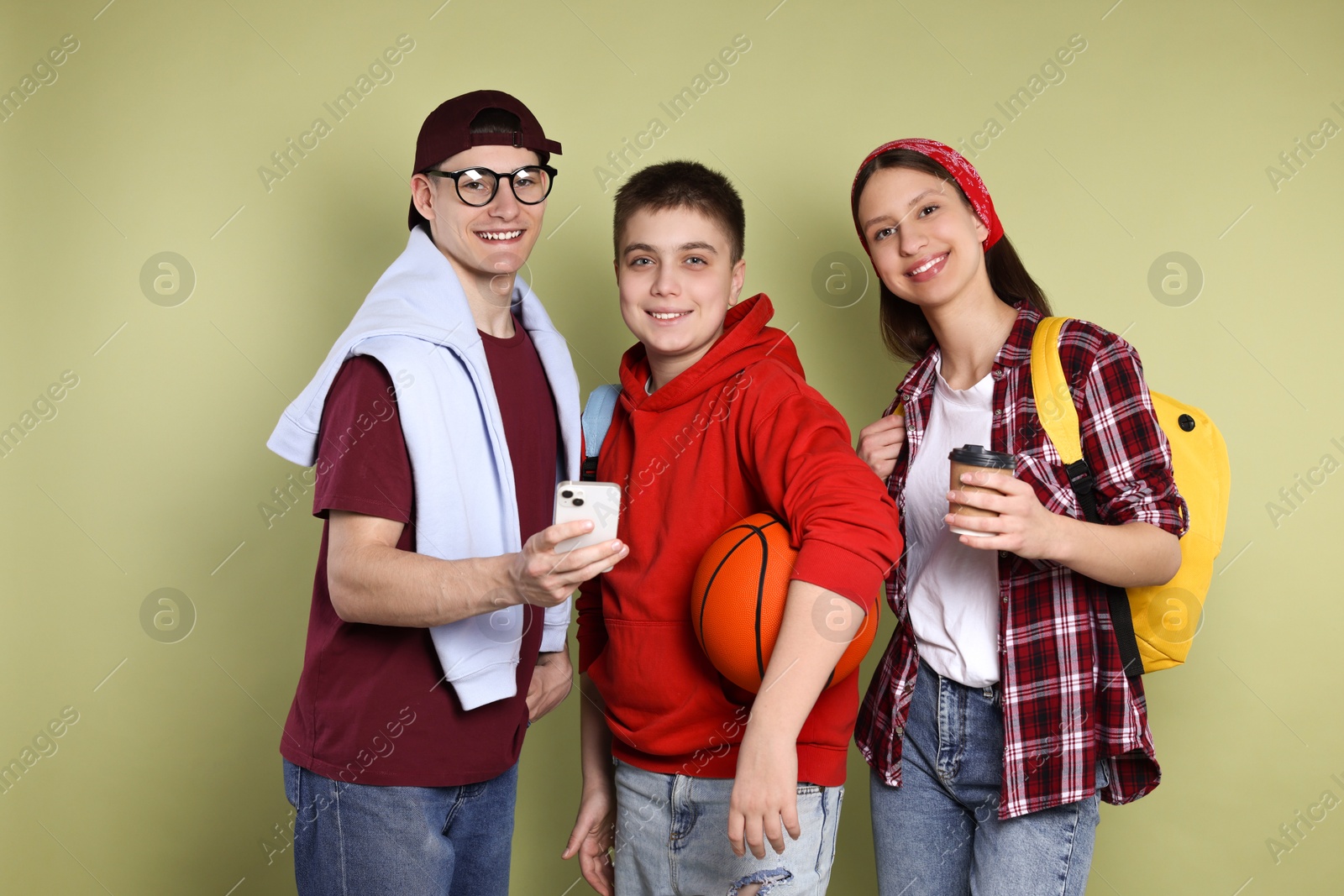 Photo of Student showing something on smartphone to his friends against olive background