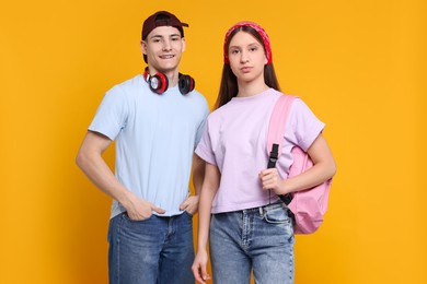 Portrait of stylish students on orange background