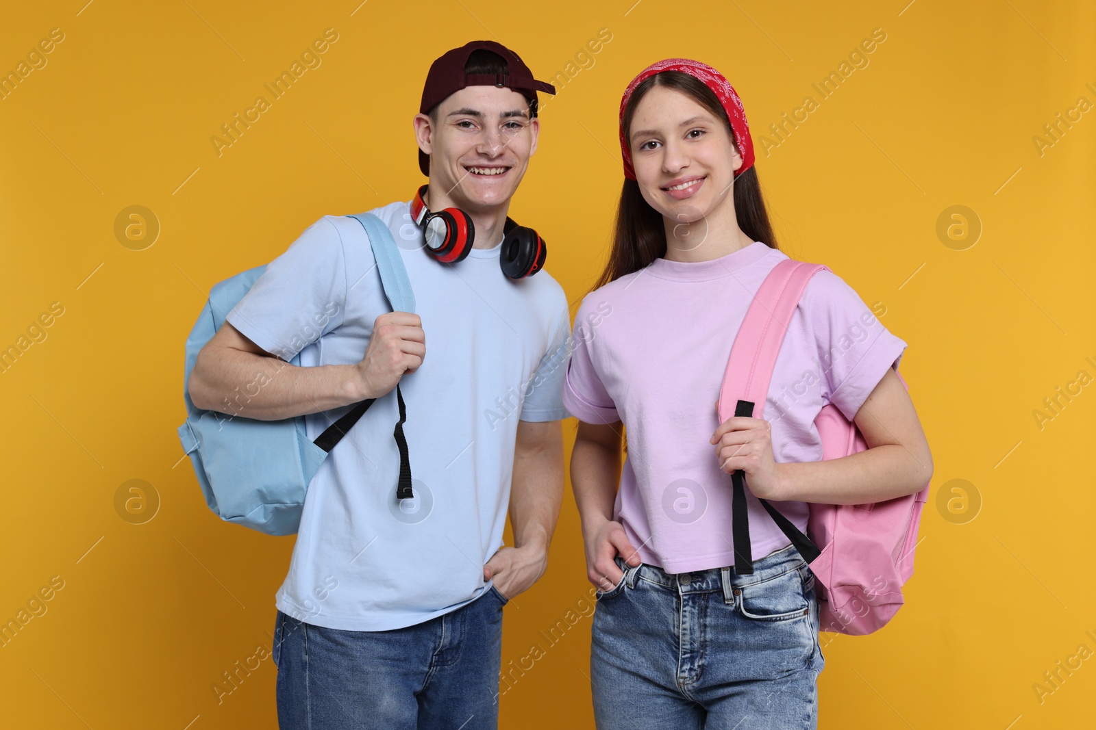 Photo of Portrait of students with backpacks on orange background