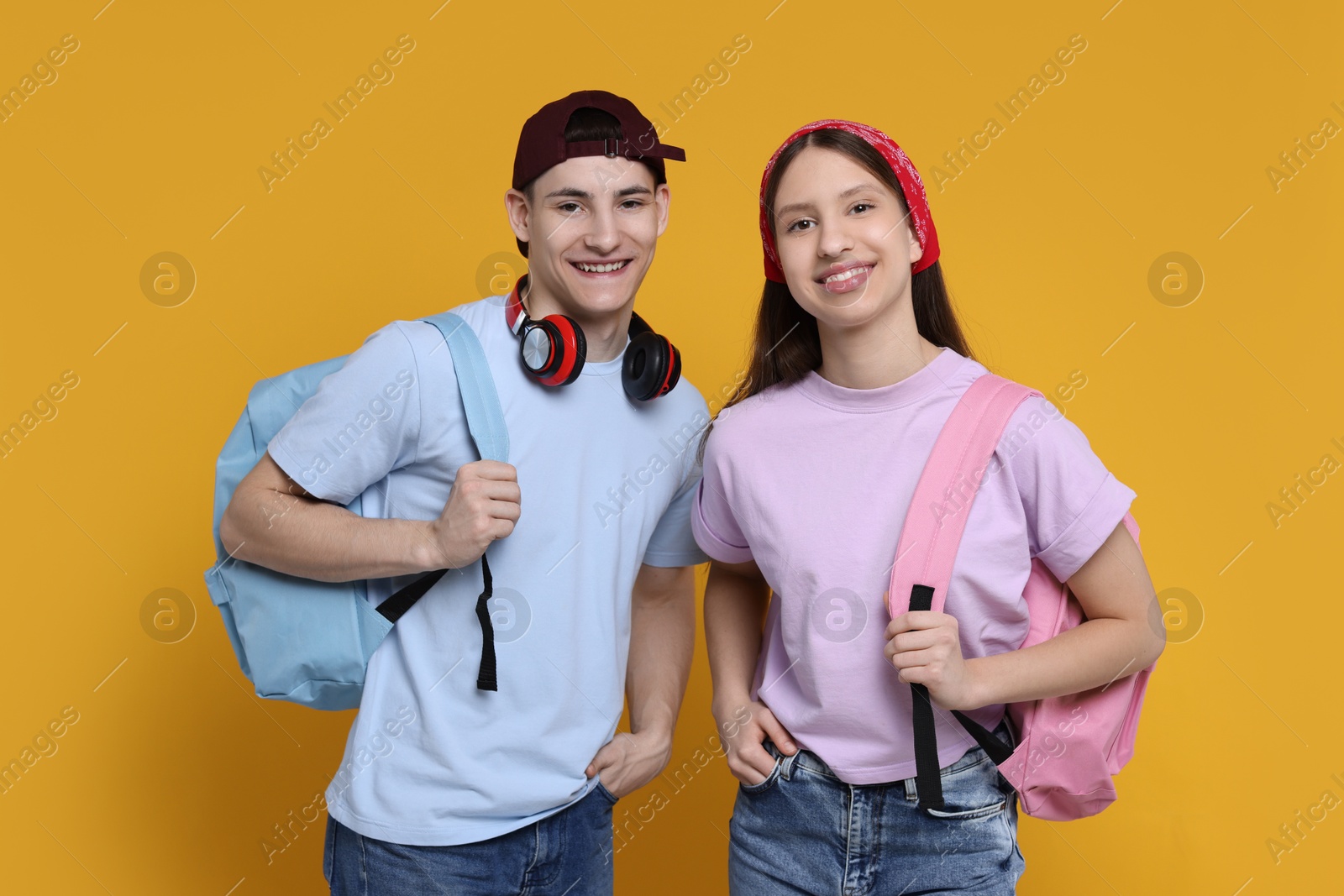 Photo of Portrait of students with backpacks on orange background