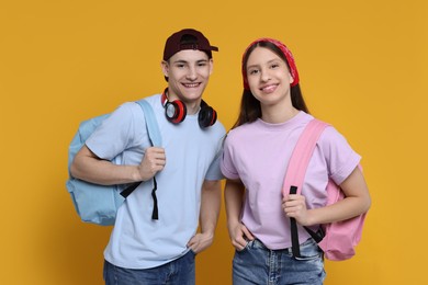 Portrait of students with backpacks on orange background