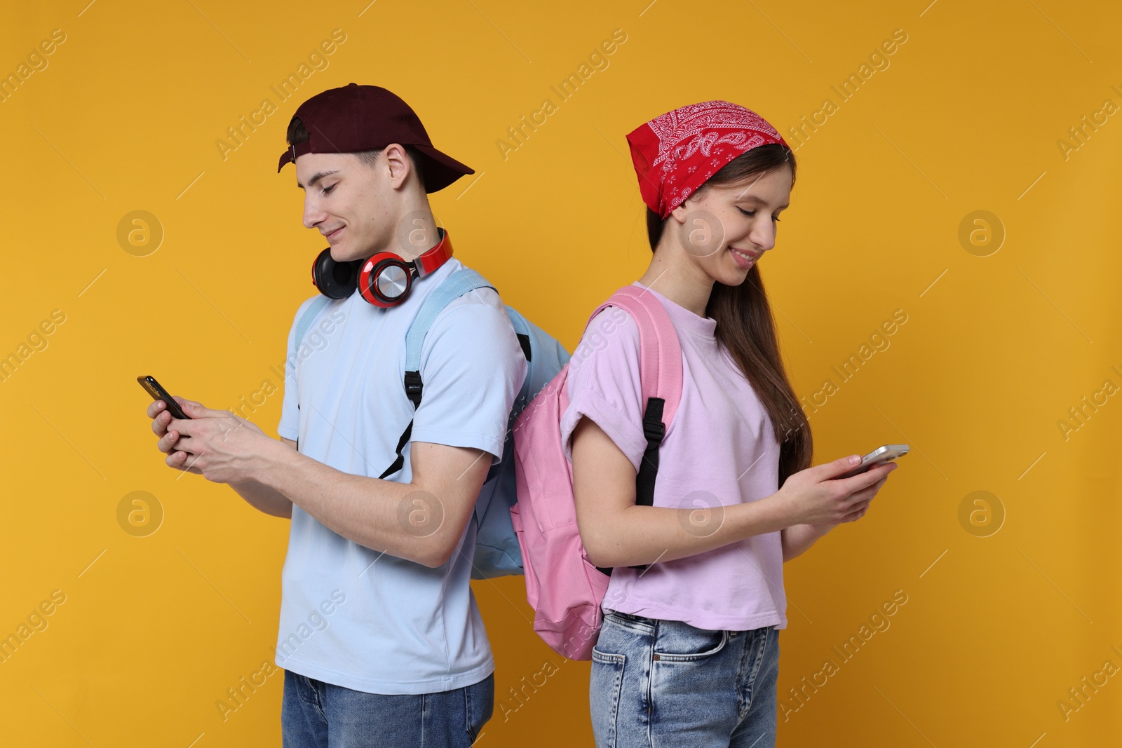 Photo of Portrait of students with smartphones on orange background