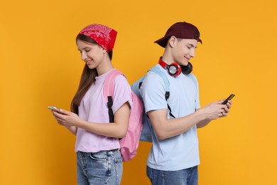 Photo of Portrait of students with smartphones on orange background