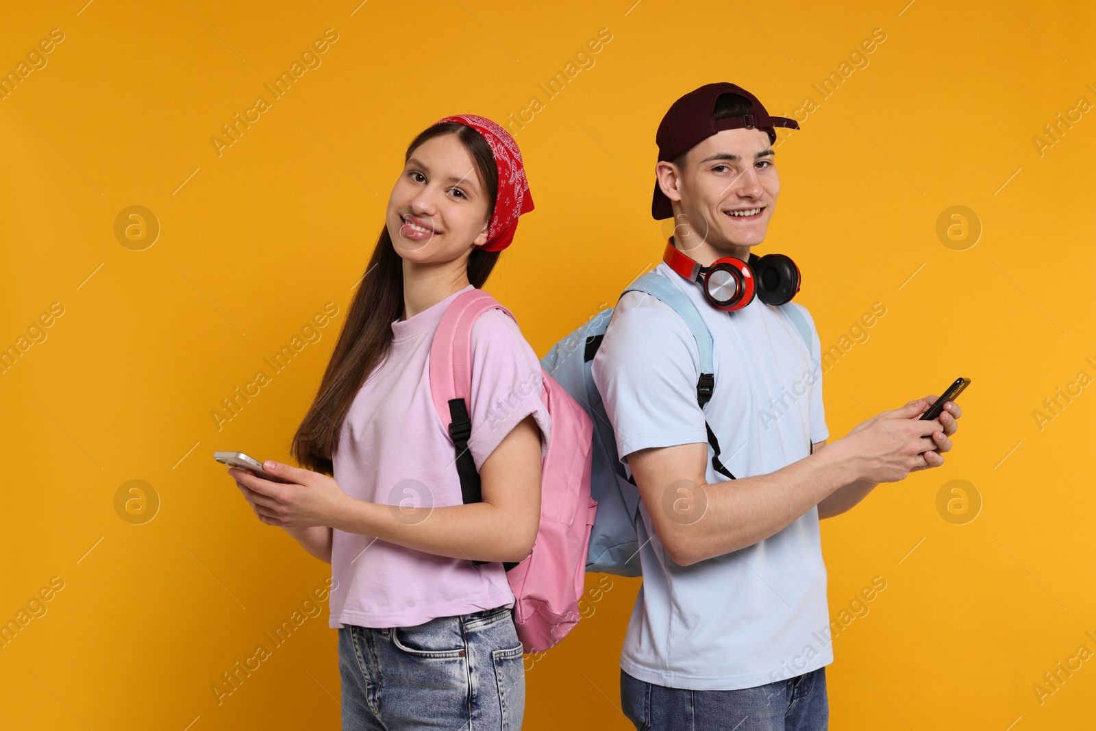 Photo of Portrait of students with smartphones on orange background