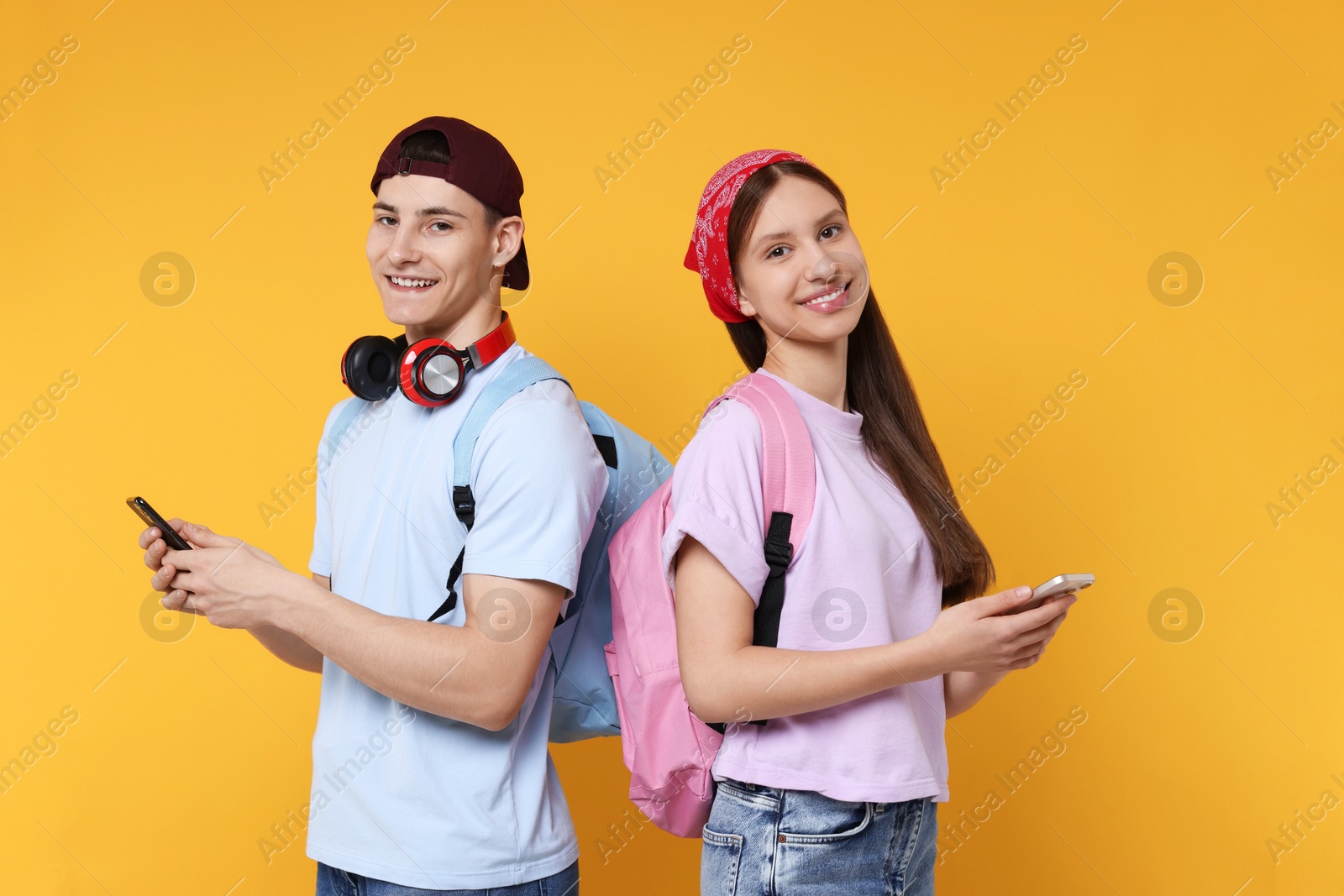 Photo of Portrait of students with smartphones on orange background