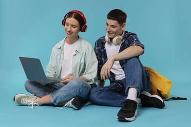 Students with laptop and headphones on light blue background