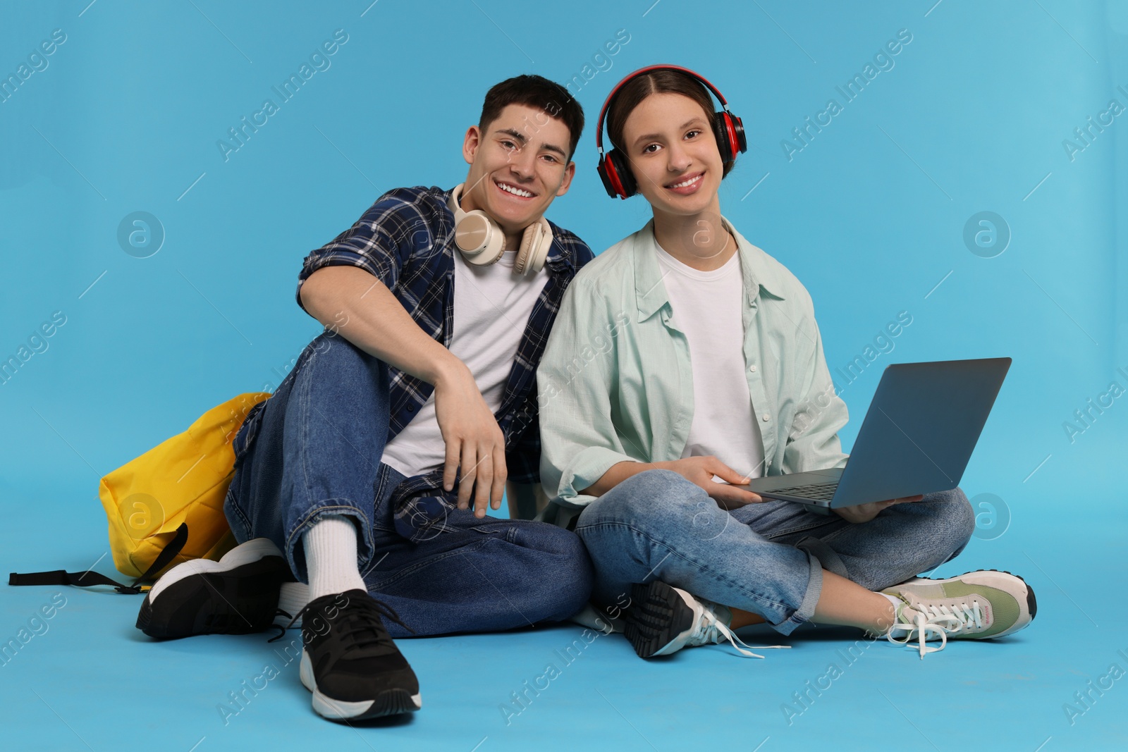 Photo of Students with laptop and headphones on light blue background