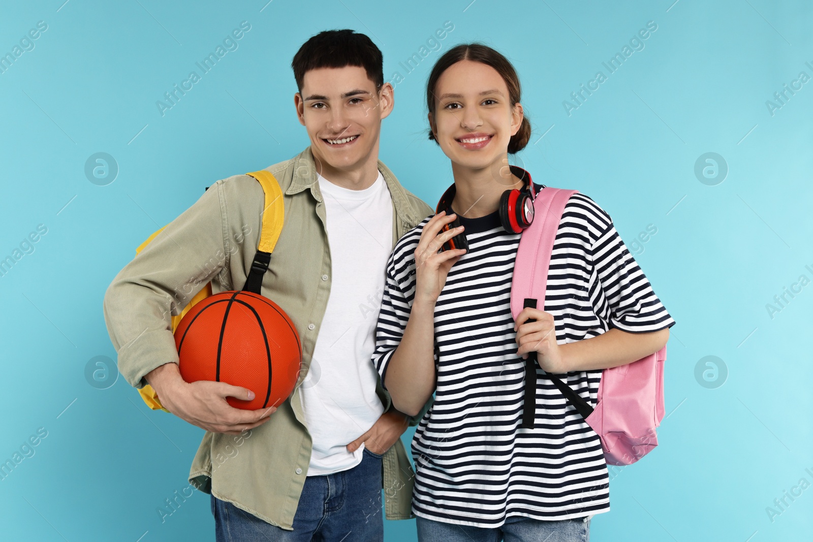 Photo of Students with backpacks and basketball ball on light blue background