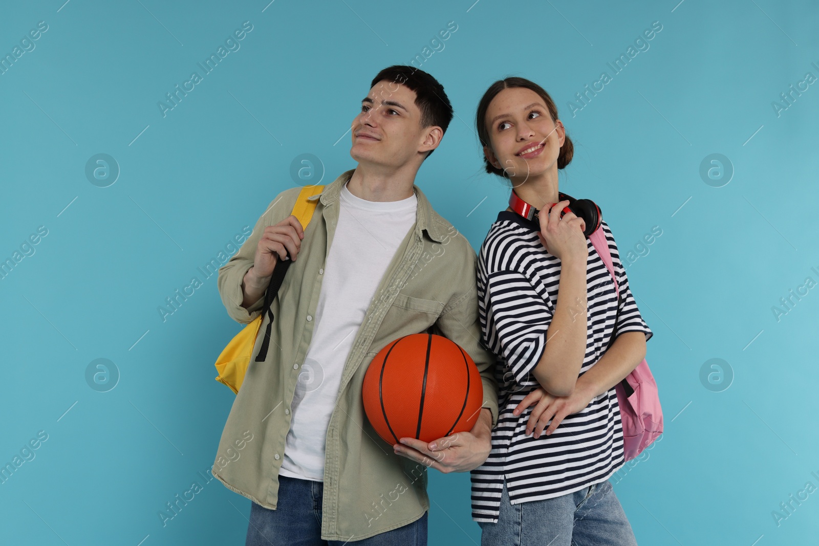 Photo of Students with backpacks and basketball ball on light blue background