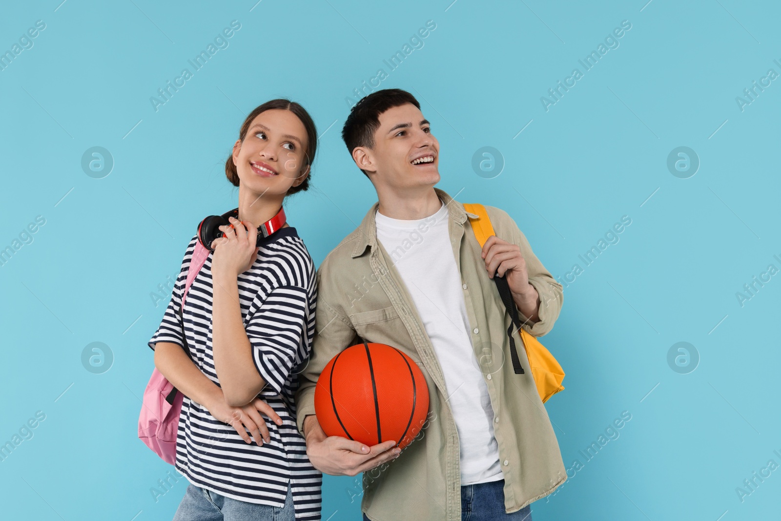 Photo of Students with backpacks and basketball ball on light blue background