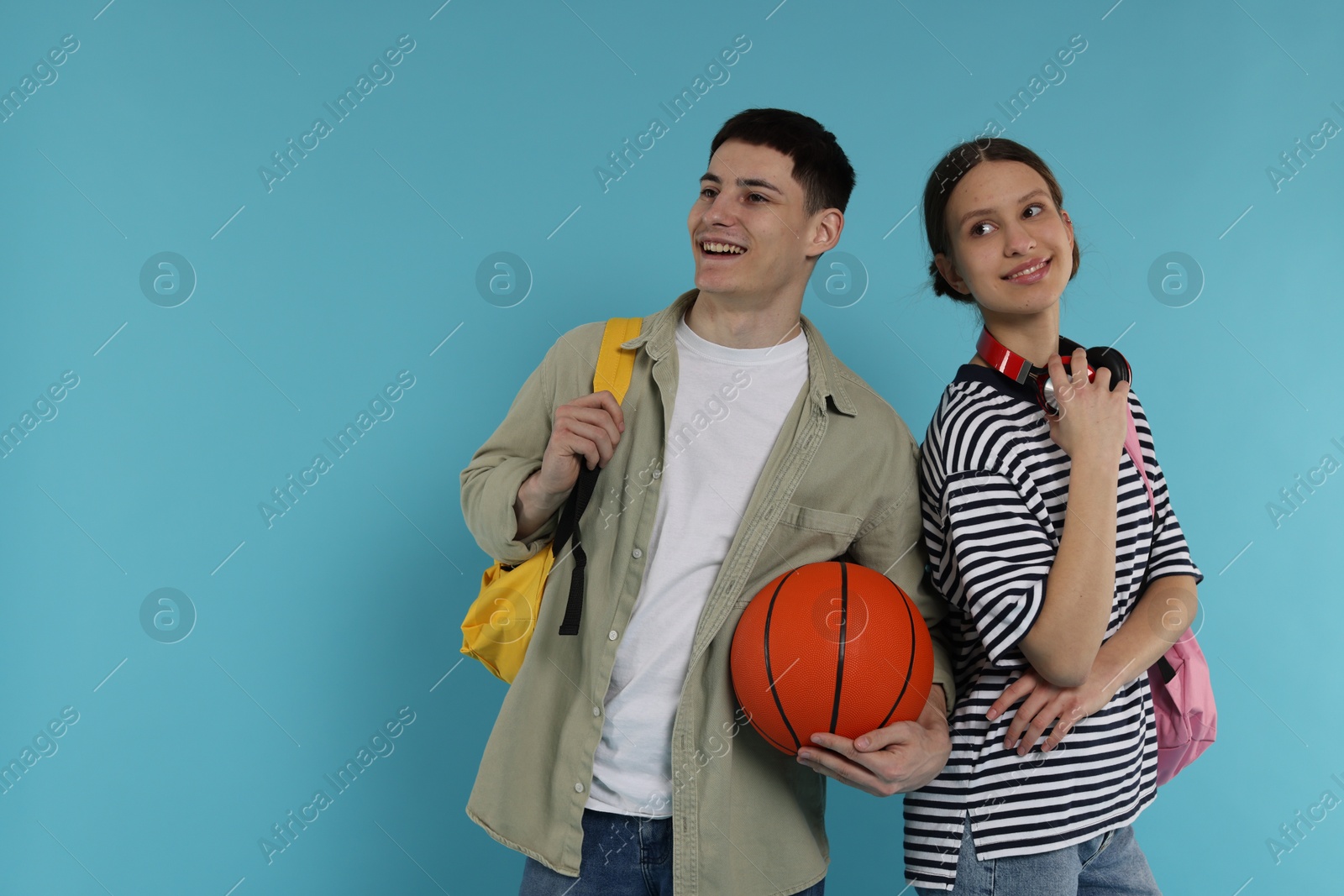 Photo of Students with backpacks and basketball ball on light blue background, space for text