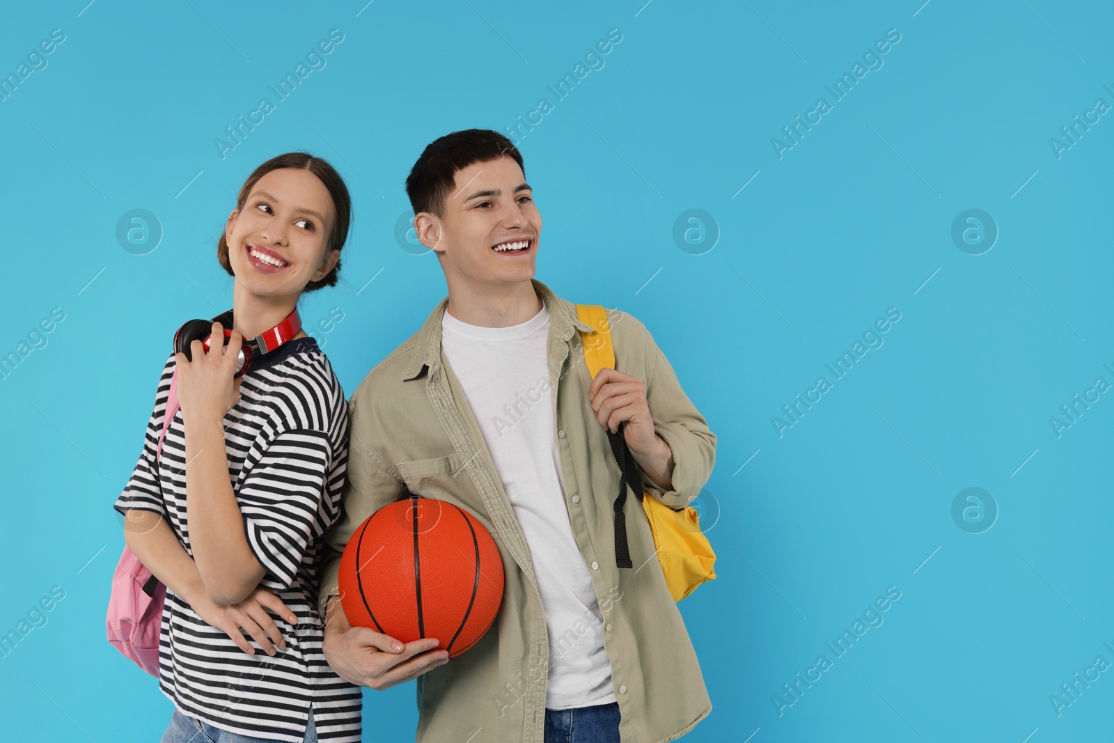 Photo of Students with backpacks and basketball ball on light blue background, space for text