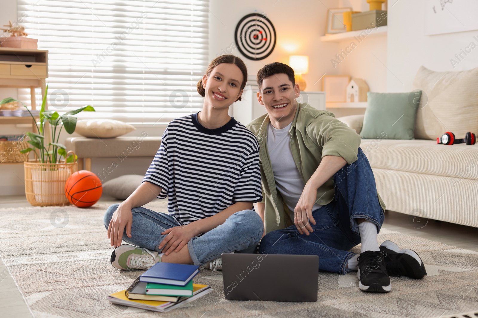 Photo of Students with laptop and books on floor at home