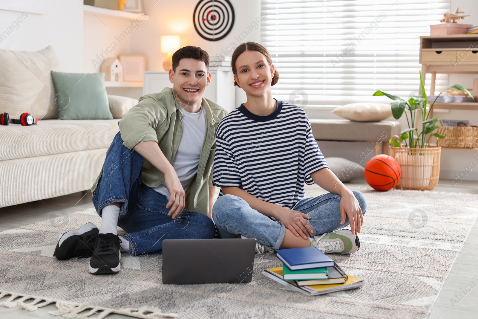 Photo of Students with laptop and books on floor at home