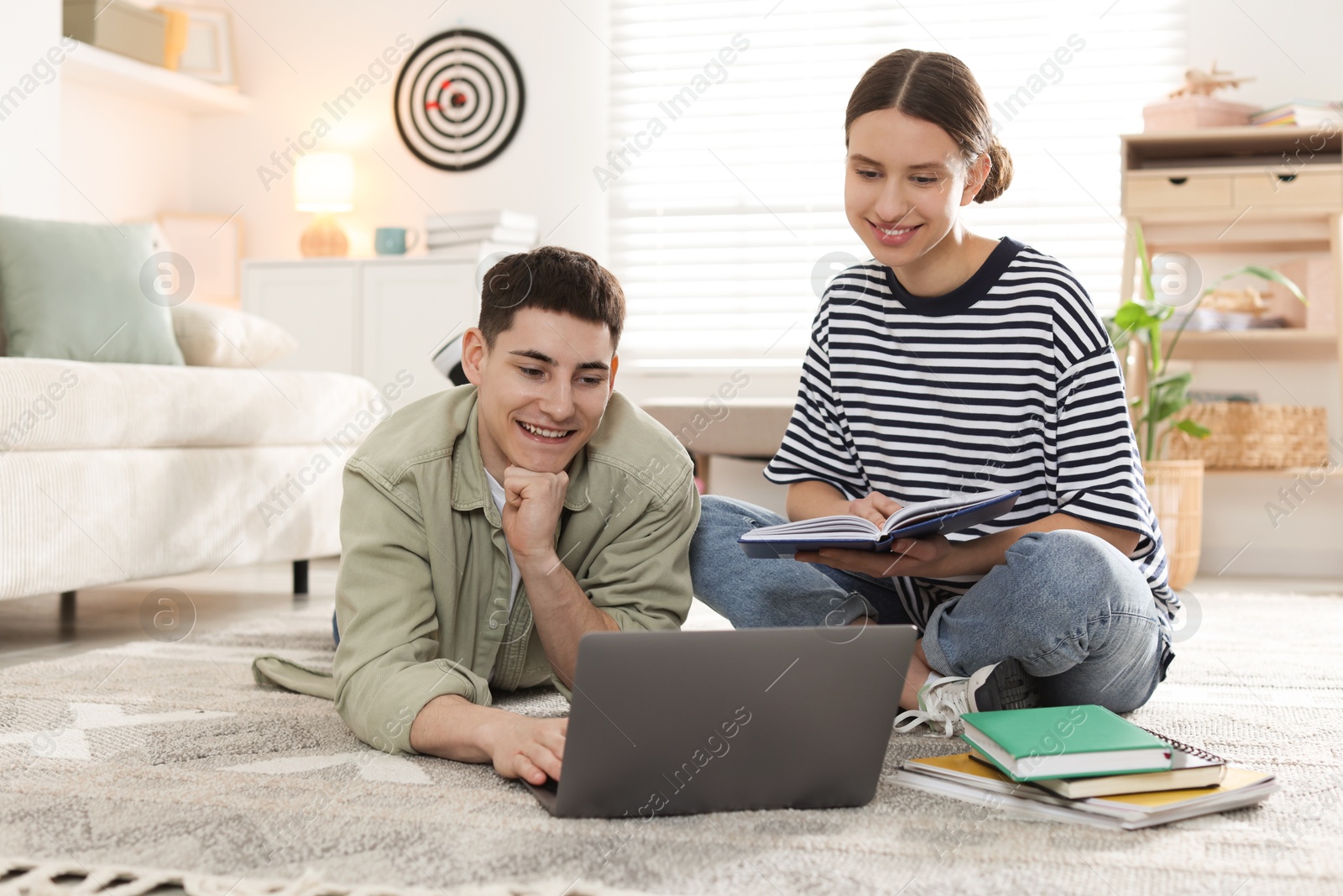 Photo of Students doing homework with laptop on floor at home