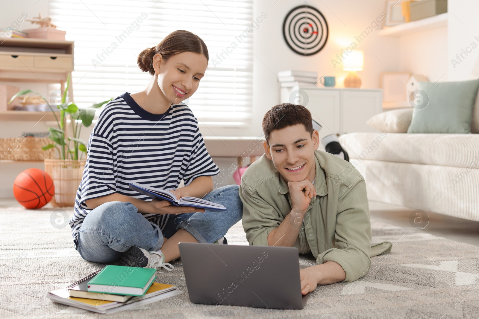 Photo of Students doing homework with laptop on floor at home