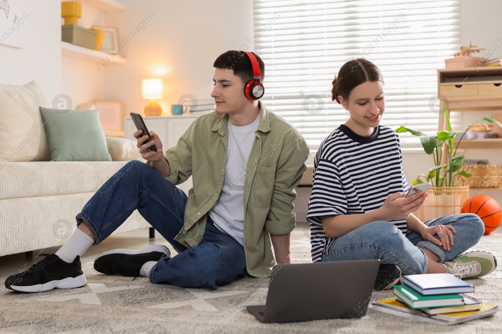 Photo of Students with smartphones on floor at home