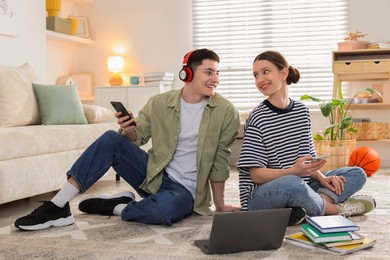 Photo of Students with smartphones on floor at home