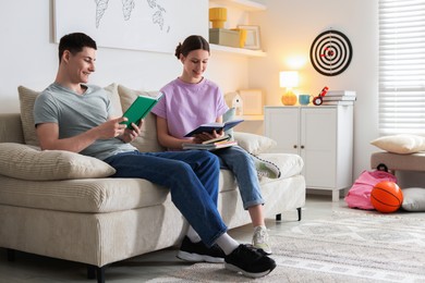 Students doing homework with books on sofa at home