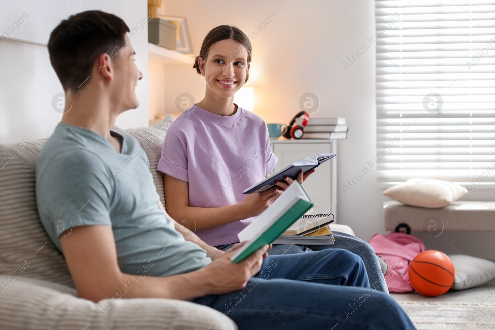 Photo of Students doing homework with books on sofa at home