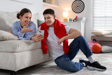 Photo of Student showing something on smartphone to his friend at home