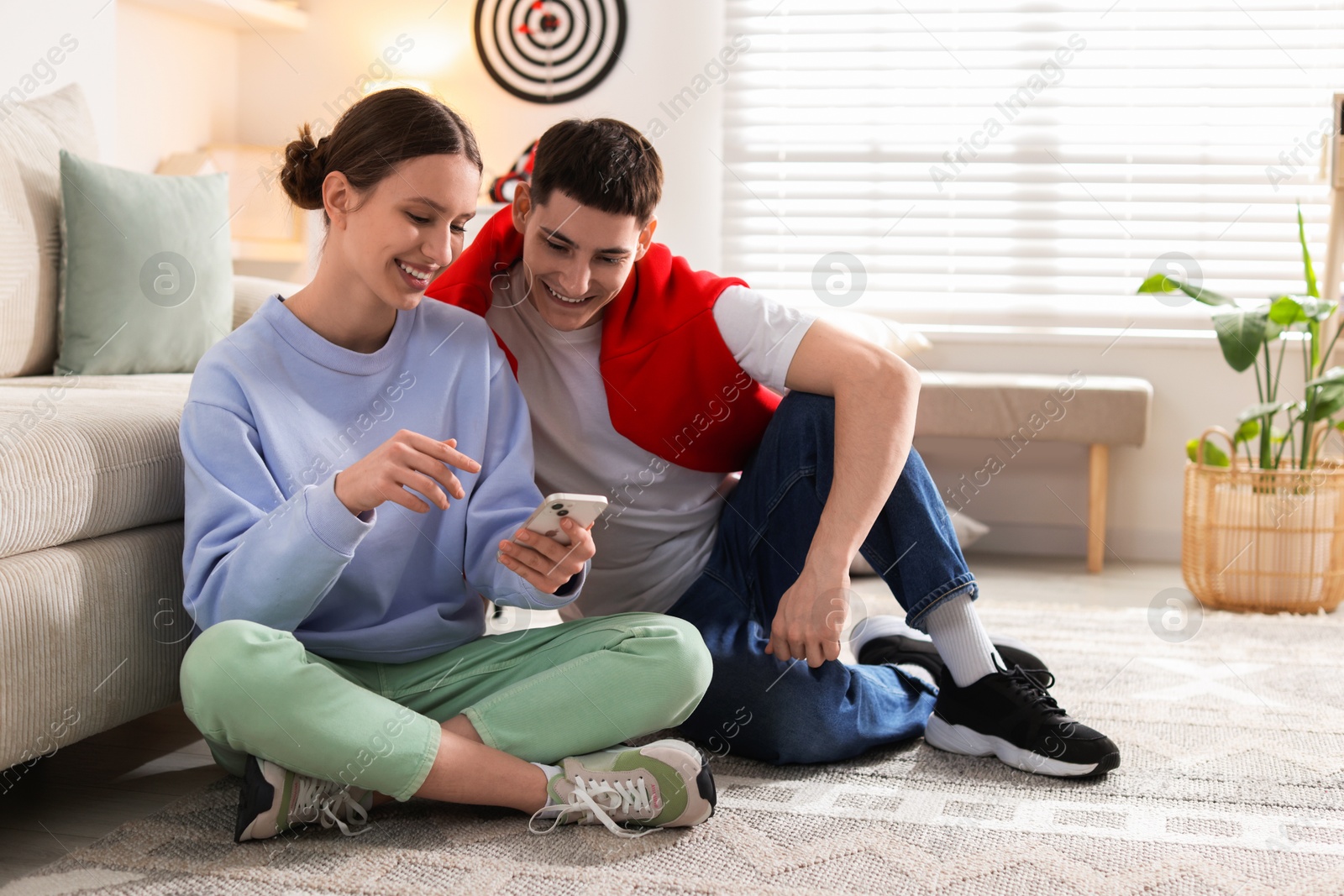 Photo of Teenage girl showing something on smartphone to her friend at home