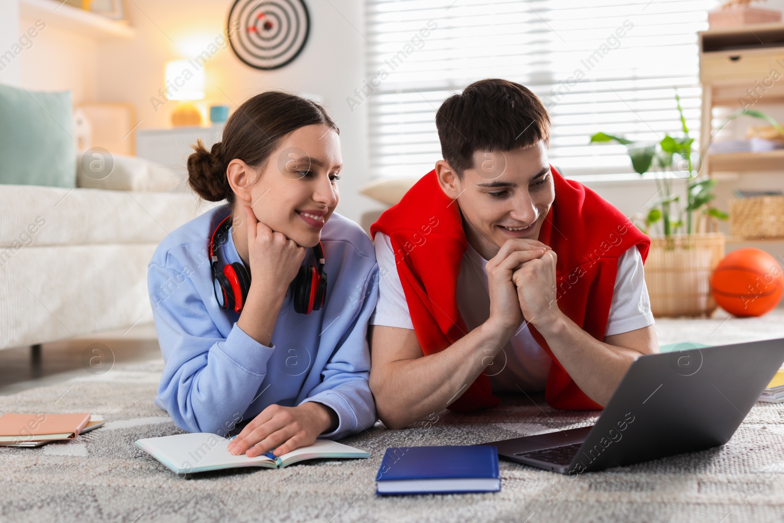 Photo of Students doing homework with laptop on floor at home