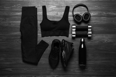 Photo of Flat lay composition with black sportswear and sneakers on wooden background