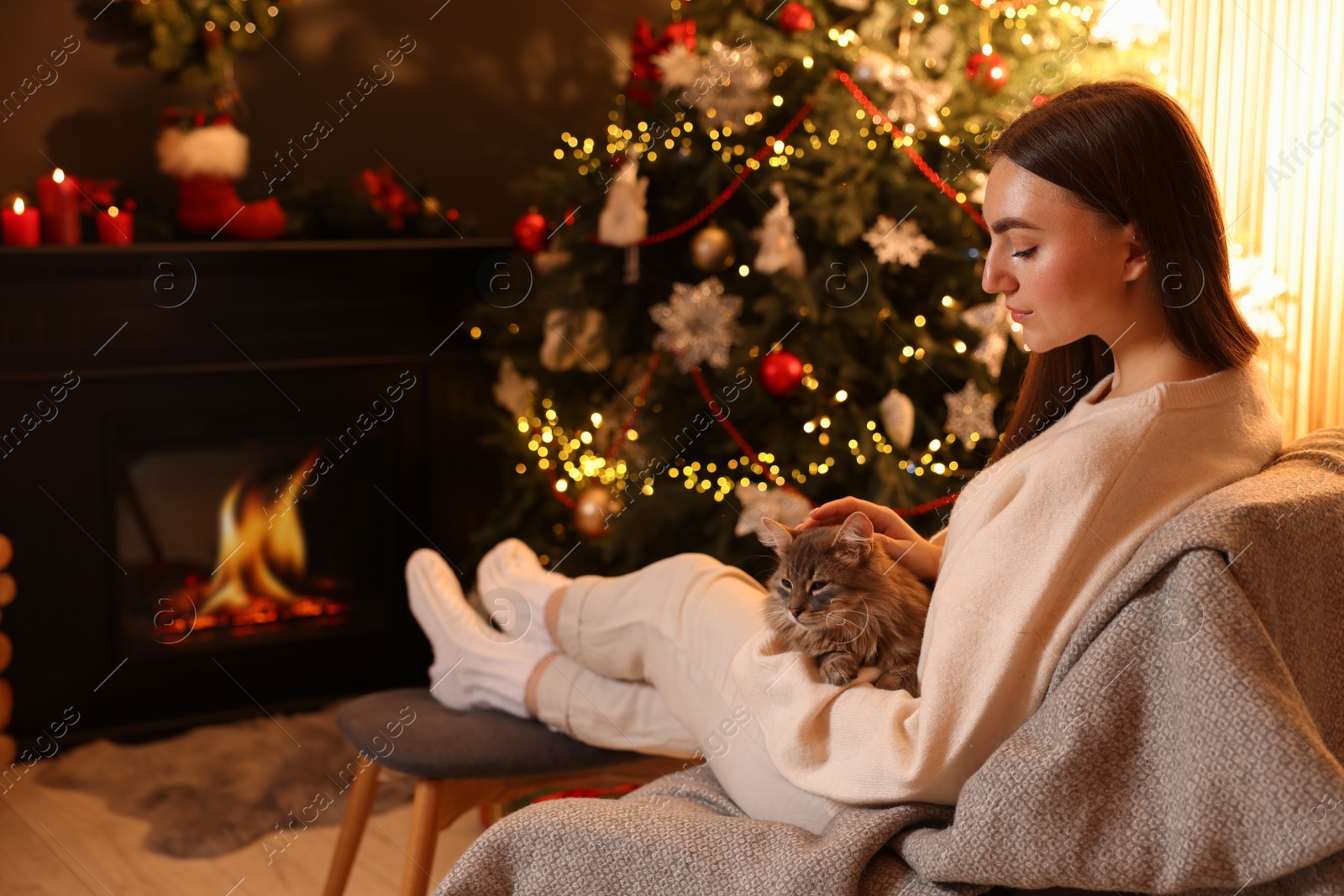 Photo of Woman with cute cat in room decorated for Christmas, space for text