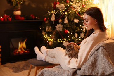 Photo of Woman with cute cat in room decorated for Christmas, space for text