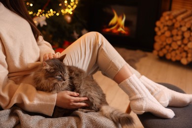 Photo of Woman with cute cat in room decorated for Christmas, closeup